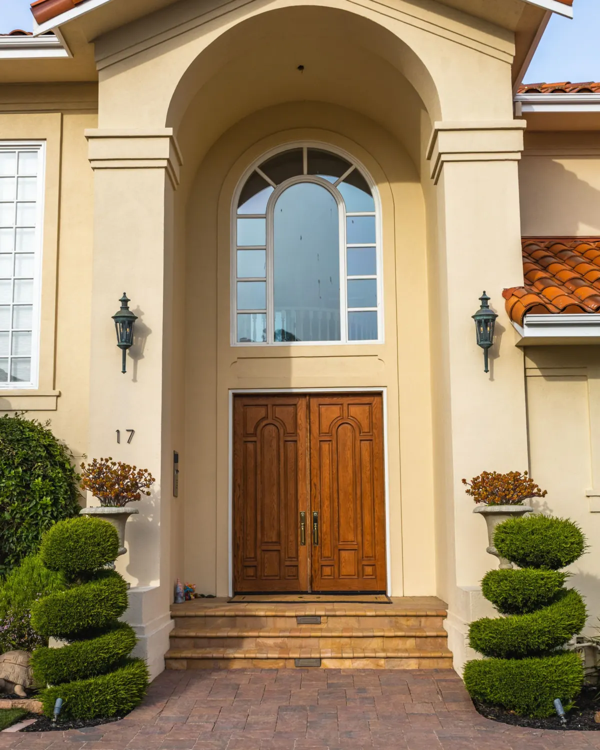 Arched stucco entry with a wooden double front door and an arched glass panel above