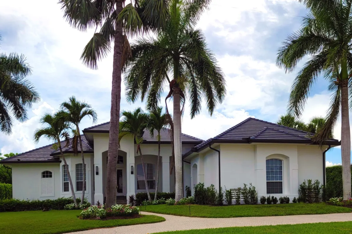 Large white stucco house with arched windows on a wide lawn among palms