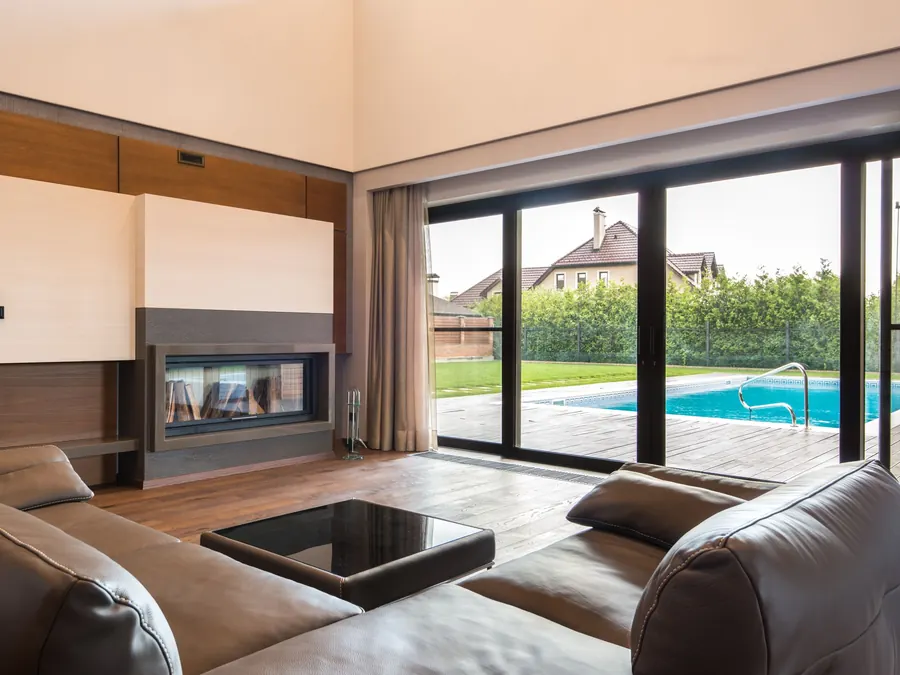 Wall of dark-framed sliding glass doors opening onto a pool deck