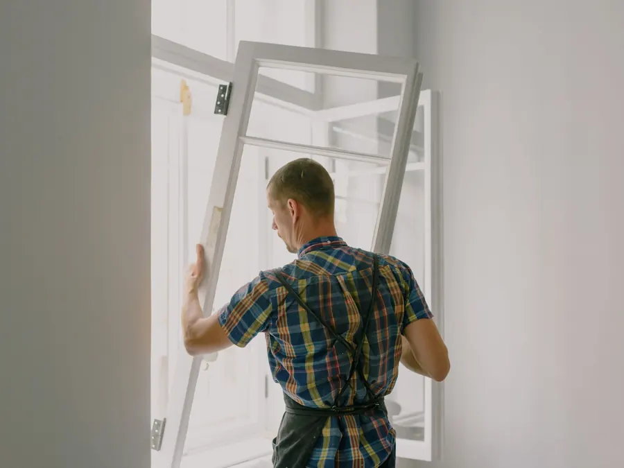 Installer lifting a window sash into its frame